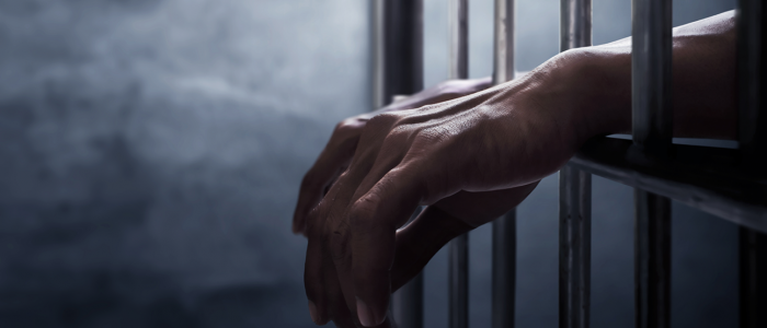 Hands resting on prison bars
